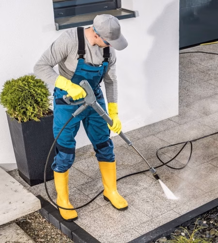 Caucasian Men Pressure Washing His House Surrounding Using Powerful Washer. Small Architecture Cleaning.