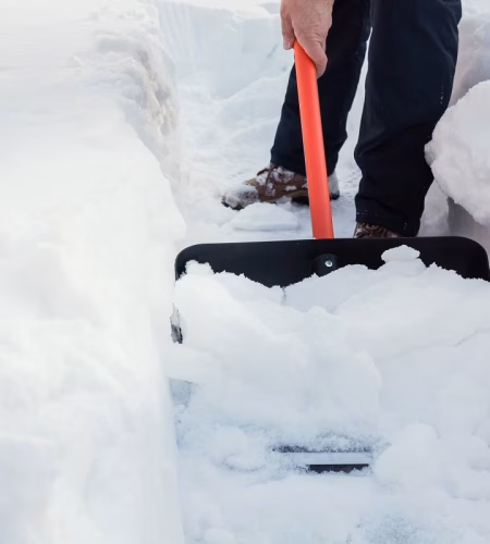 Snow removal. Man clearing snow by shovel after snowfall. Outdoors.